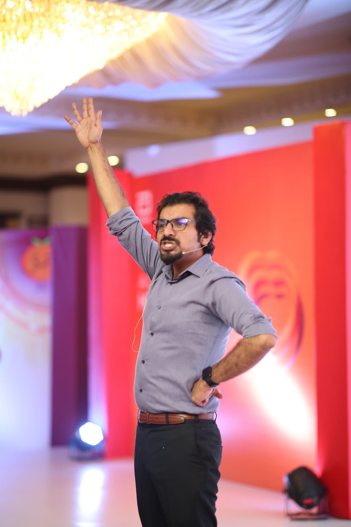 Umair Jaliawala on stage, one hand raised, mid-talk