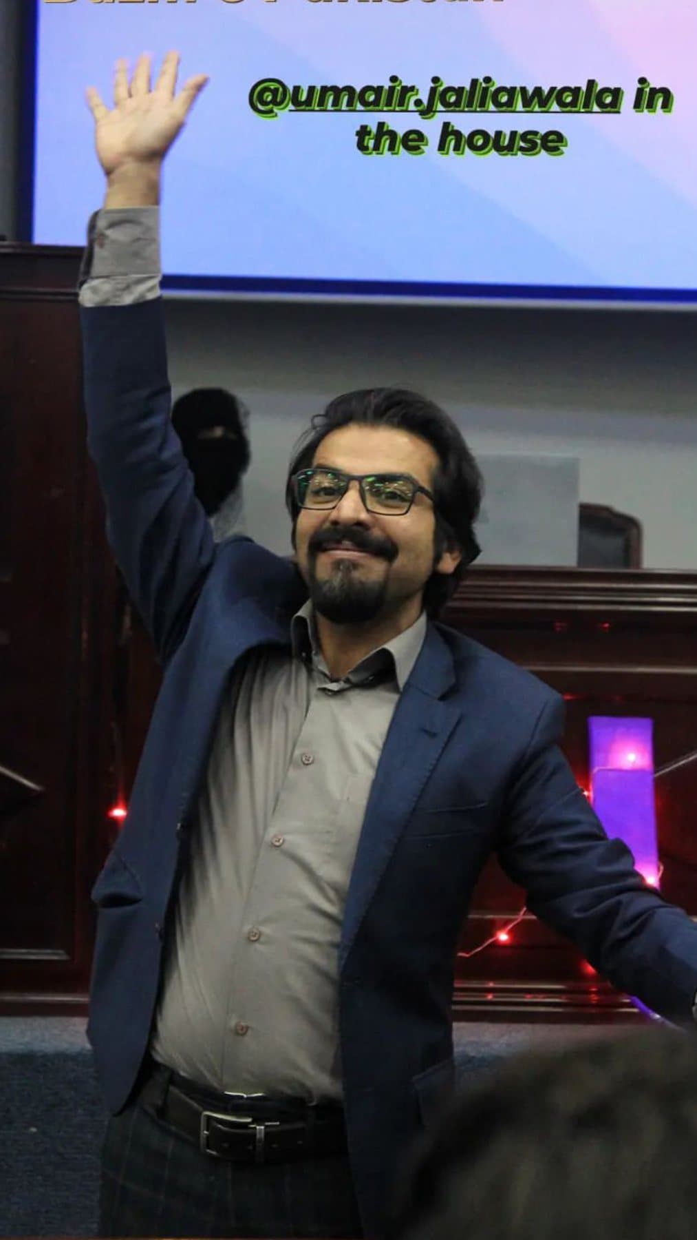Umair waving to a student audience at a university society event